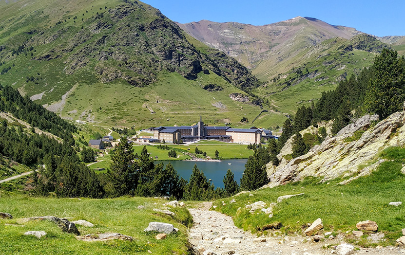 La Valle de Núria circondata da prati verdi con il Santuario e il bacino al centro.